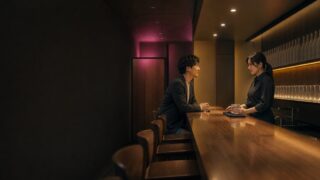 客のいない夜のバーで氷を整える29歳店員と話す30代男性