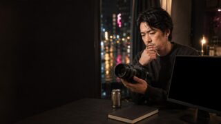 雨の夜に無地のカメラと黒い画面を見比べる30代男性